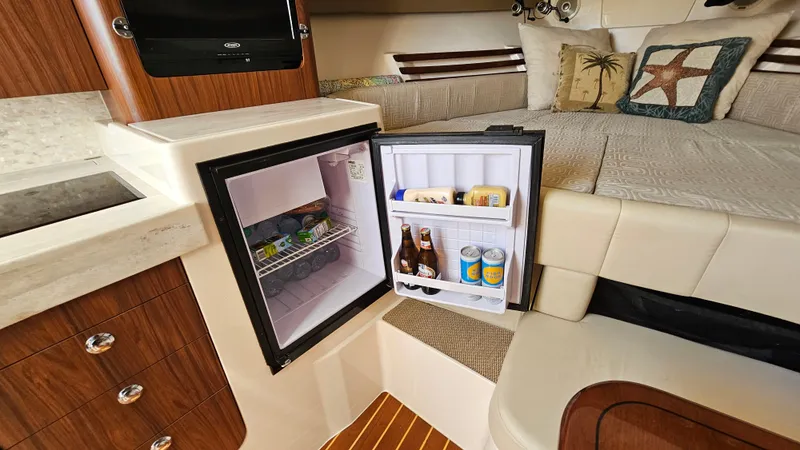 Slide: The Image of Interior of 2016 Grady-White Express 330 with open mini fridge and cozy seating area. - 44