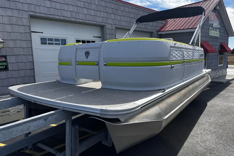 Slide: The Image of 2025 Avalon 2185 Aura Quad Lounge Twin Toon pontoon boat on trailer, outdoor setting. - 3