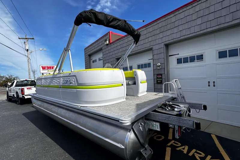 Slide: The Image of 2025 Avalon 2185 Aura Quad Lounge Twin Toon pontoon boat parked outside a garage. - 5