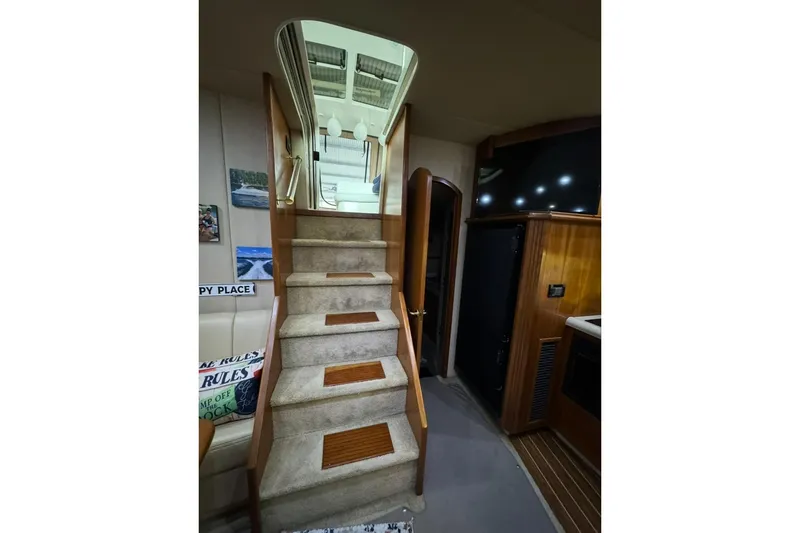Slide: The Image of Interior stairs of 2003 Cruisers Yachts 4370 Express, featuring carpet and wood accents. - 12