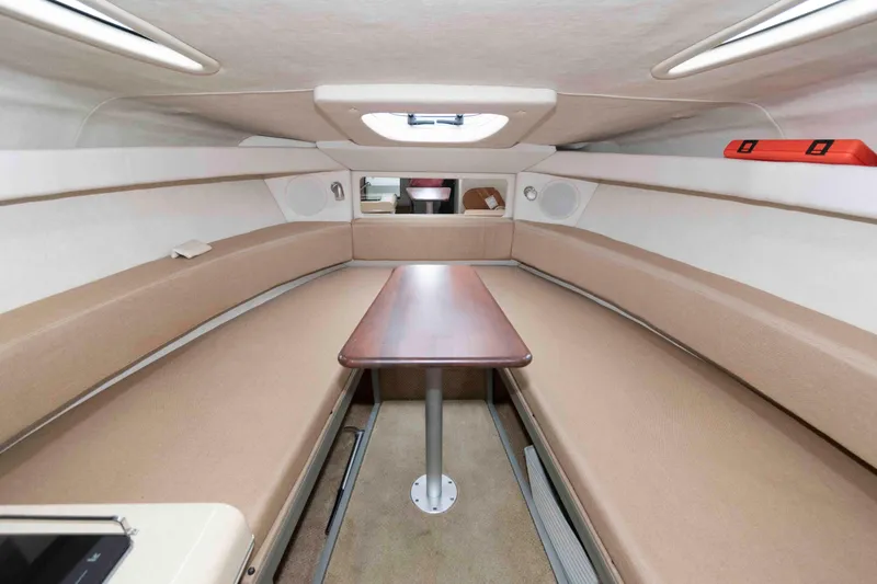 Slide: The Image of Interior of 2009 Sea Ray 250 Sundancer boat with beige seating and wooden table. - 10