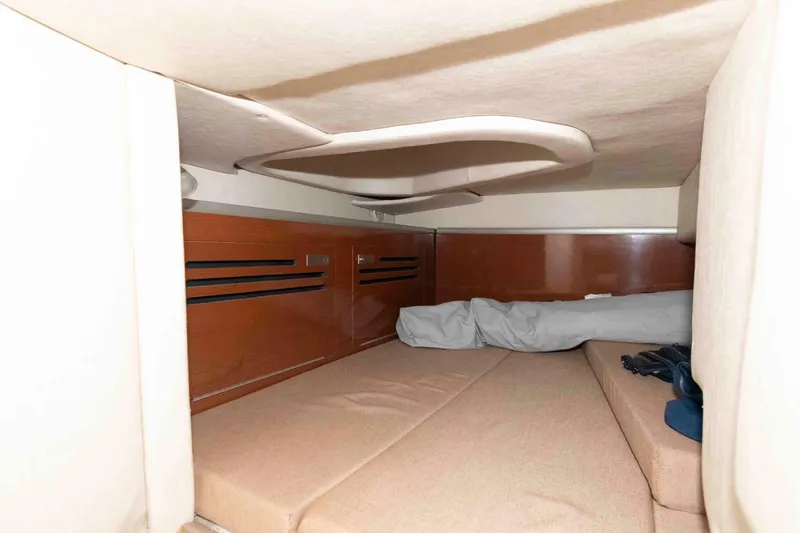Slide: The Image of 2009 Sea Ray 250 Sundancer cabin interior with cozy sleeping area and wooden accents. - 11