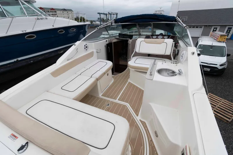 Slide: The Image of 2009 Sea Ray 250 Sundancer boat interior with seating and sink, docked at marina. - 2