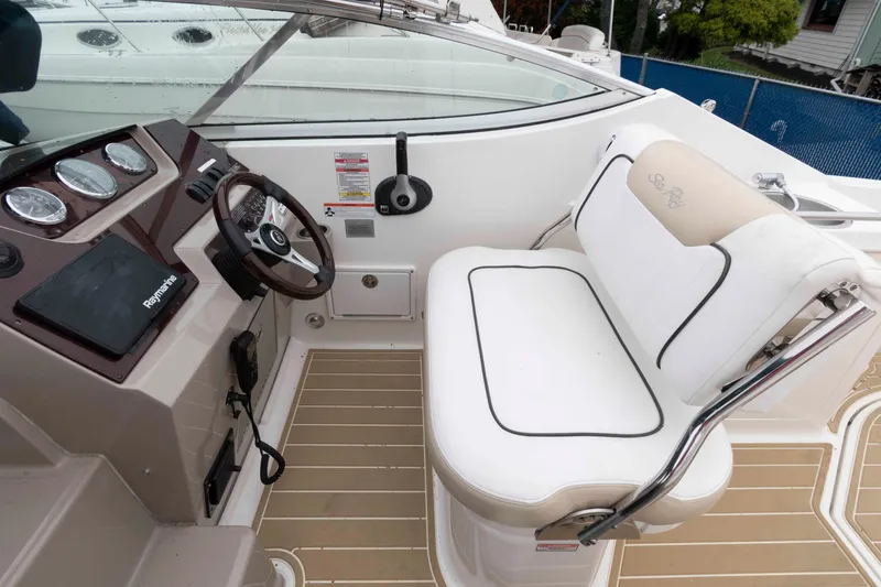 Slide: The Image of 2009 Sea Ray 250 Sundancer helm with steering wheel, gauges, and white seating. - 5