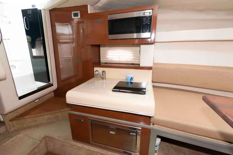 Slide: The Image of 2009 Sea Ray 250 Sundancer interior with kitchenette, microwave, and seating area. - 9