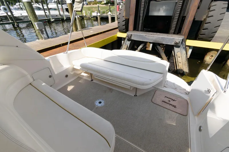 Slide: The Image of 2002 Sea Ray 340 Sundancer boat interior with white seating and dock view. - 9