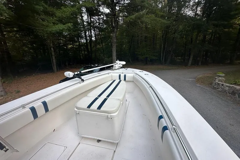 Slide: The Image of 2006 Contender 27 CC boat with cushioned seating, parked near a wooded area. - 10