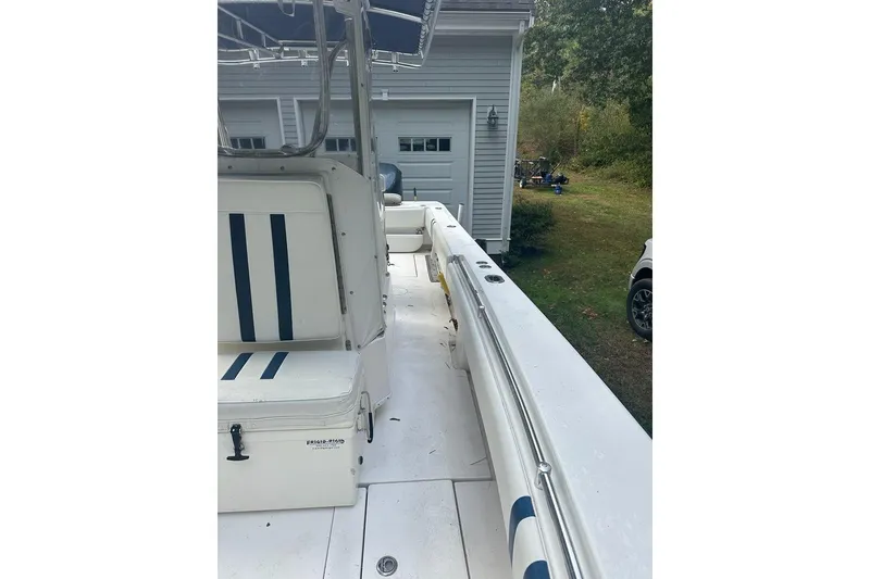 Slide: The Image of 2006 Contender 27 CC boat interior with striped seating, parked near a garage. - 14
