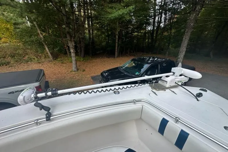 Slide: The Image of 2006 Contender 27 CC boat with trolling motor, parked near trees and vehicles. - 15