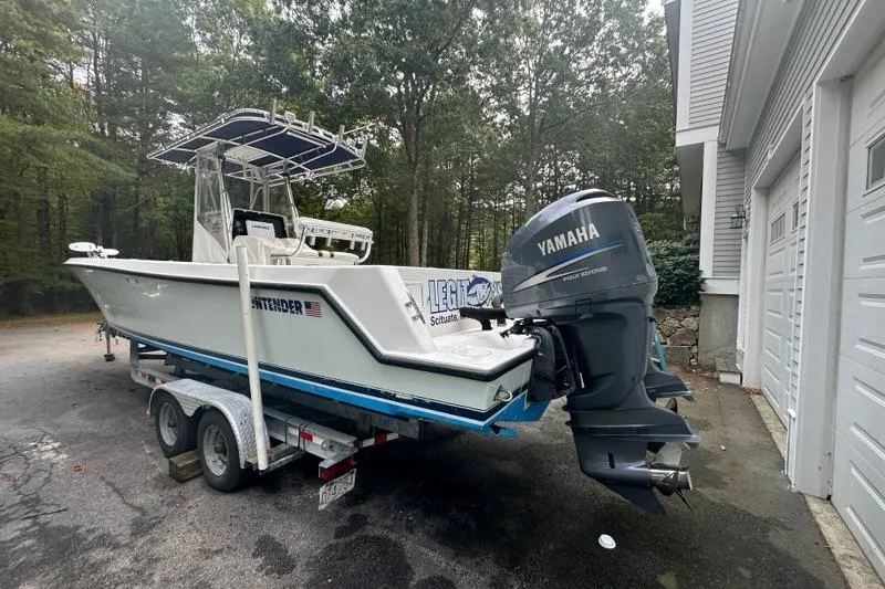 Slide: The Image of 2006 Contender 27 CC boat on trailer with Yamaha outboard motor, parked near garage. - 2