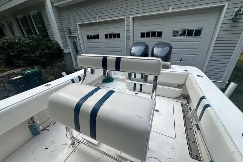 Slide: The Image of 2006 Contender 27 CC boat with striped seating, parked near a garage. - 7