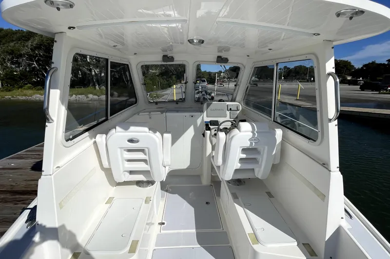 Slide: The Image of 2024 NorthCoast 235 boat interior with helm, seating, and windows at a dock. - 13