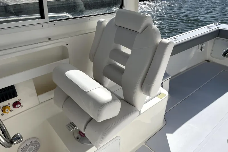 Slide: The Image of 2024 NorthCoast 235 boat interior with white cushioned seating by the water. - 14