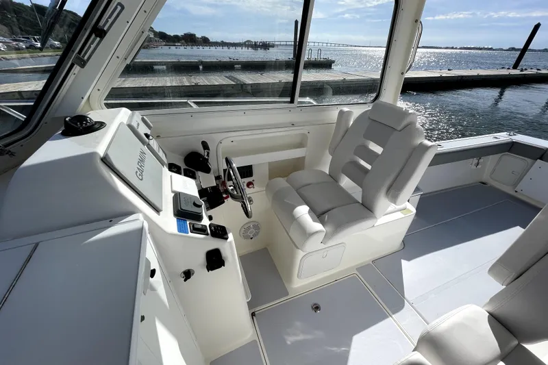 Slide: The Image of 2024 NorthCoast 235 boat interior with helm, seating, and waterfront view. - 16