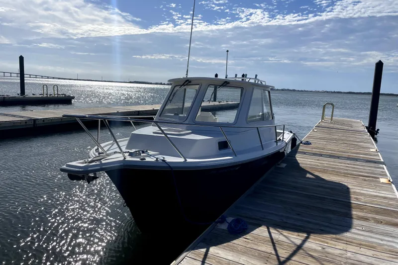 Slide: The Image of 2024 NorthCoast 235 boat docked on a sunny day with scenic water view. - 2