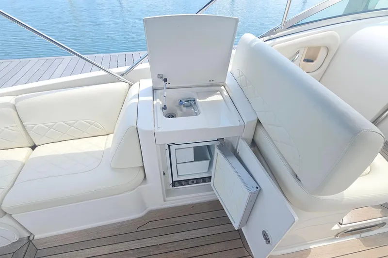 Slide: The Image of 2006 Chris-Craft Corsair 36 interior with white seating, sink, and mini fridge. - 9