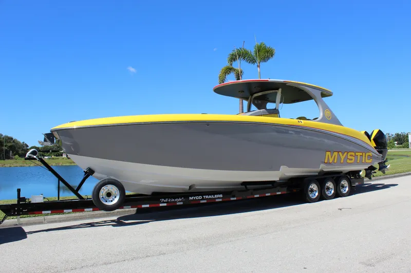 The Image of 2021 Mystic M4200 boat on trailer, yellow and gray design, parked near water. - 0