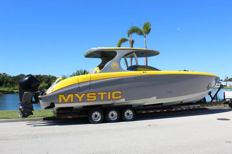 Slide: The Image of 2021 Mystic M4200 boat on trailer, yellow and gray design, parked by a lake. - 11