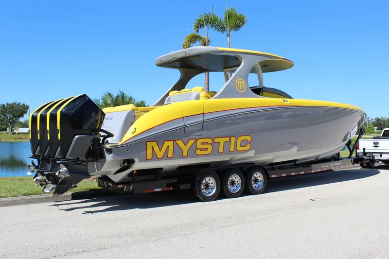 Slide: The Image of 2021 Mystic M4200 boat on trailer, yellow and gray design, parked near water. - 12