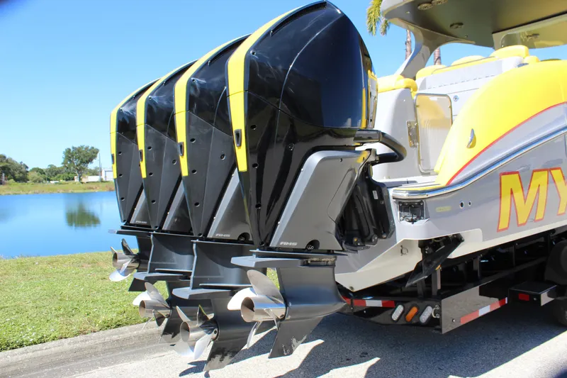 Slide: The Image of 2021 Mystic M4200 boat with four powerful outboard engines, docked by a serene lake. - 16