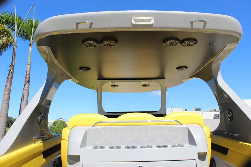 Slide: The Image of 2021 Mystic M4200 boat interior with yellow seating and overhead speakers, under clear blue sky. - 26