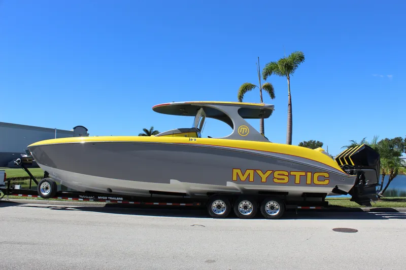 Slide: The Image of 2021 Mystic M4200 boat on trailer, yellow and gray design, palm trees in background. - 4
