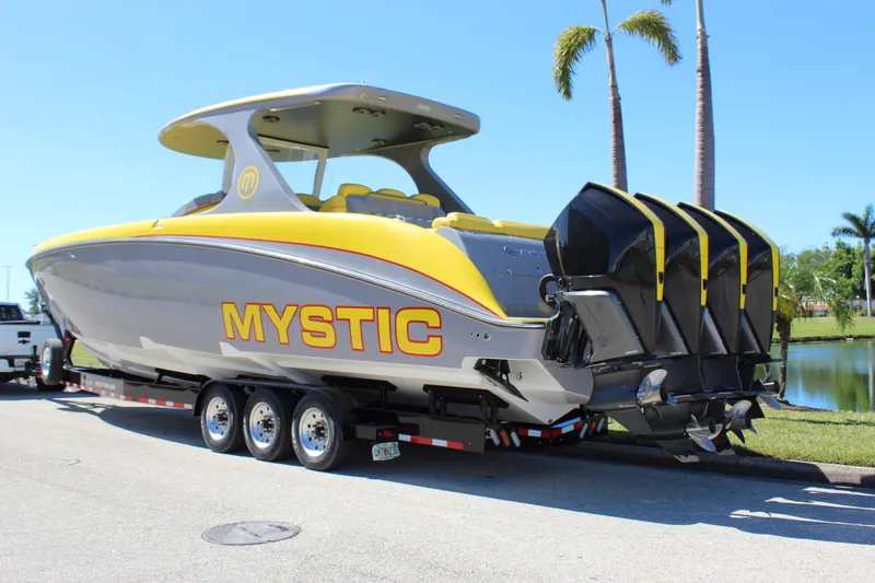 Slide: The Image of Yellow and gray 2021 Mystic M4200 boat on trailer, featuring four powerful outboard engines. - 6