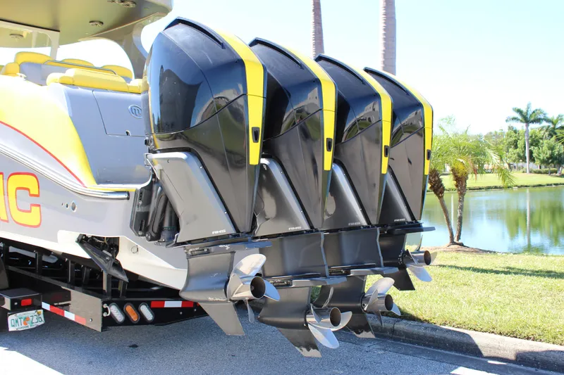 Slide: The Image of Four powerful outboard motors on a 2021 Mystic M4200 boat, parked near a scenic lake. - 7