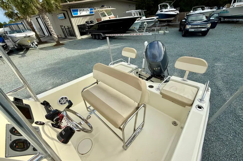 Slide: The Image of 2016 Release 180 CC boat interior with seating and motor, parked in a marina. - 16