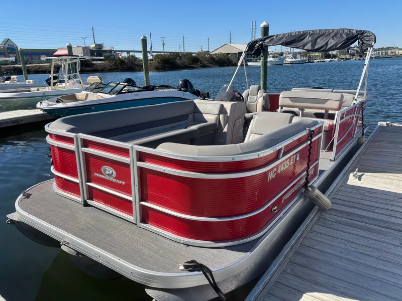 Slide: The Image of 2022 Princecraft 23 Vectra pontoon boat docked at marina, red exterior, spacious seating. - 2