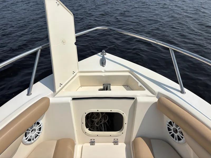 Slide: The Image of 2022 Scout 210 Dorado boat interior with open storage compartment on calm water. - 11