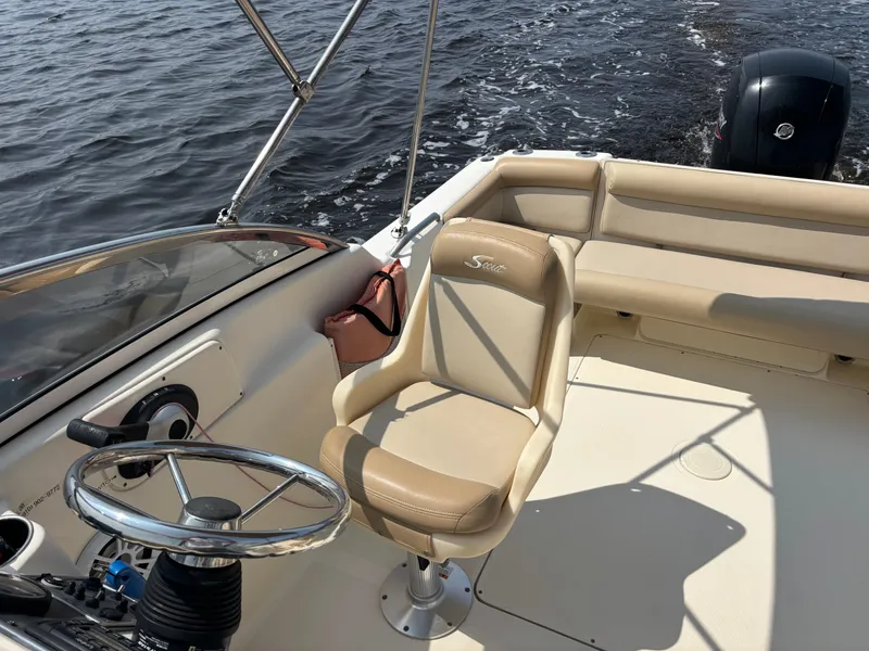 Slide: The Image of 2022 Scout 210 Dorado boat interior with steering wheel and seating, on water. - 15