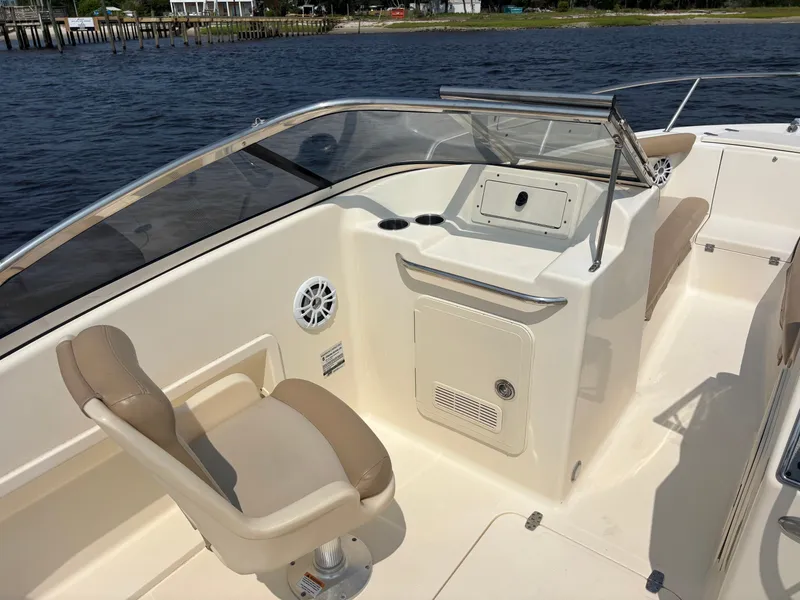 Slide: The Image of 2022 Scout 210 Dorado boat interior with beige seating and control panel, dockside view. - 24