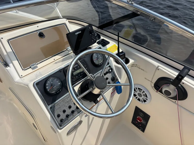 Slide: The Image of 2022 Scout 210 Dorado boat dashboard with steering wheel and navigation controls. - 27
