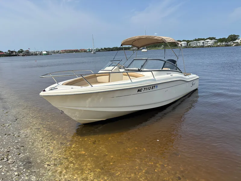 Slide: The Image of 2022 Scout 210 Dorado boat docked on a calm shoreline under a clear sky. - 3