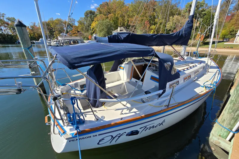 Slide: The Image of 1988 Pearson 362 Centerboard sailboat docked, featuring blue canvas covers and scenic background. - 30