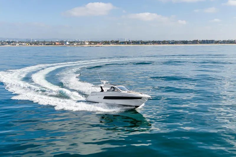 Slide: The Image of 2017 Cruisers Yachts 39 Express Coupe cruising on open water, near coastal cityscape. - 15