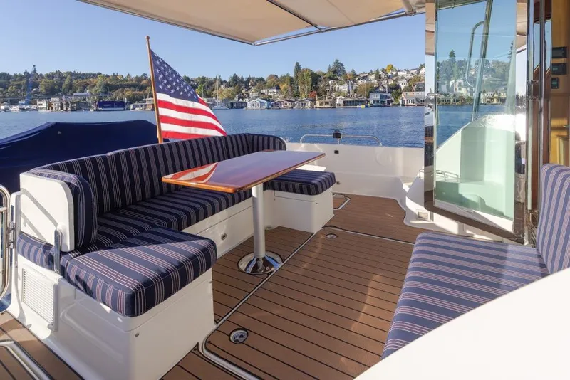 Slide: The Image of Outdoor seating area on 2020 Sabre 45 Salon Express yacht with American flag and scenic waterfront view. - 15