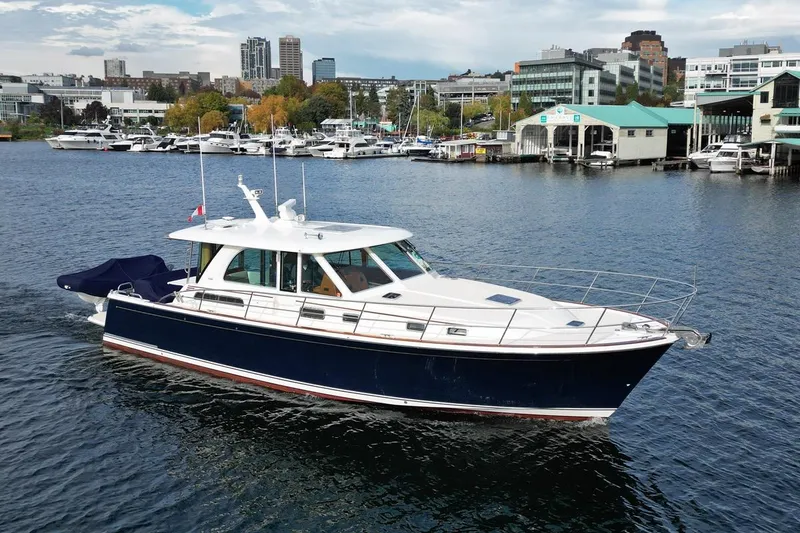 Slide: The Image of 2020 Sabre 45 Salon Express yacht cruising in a marina with cityscape background. - 2