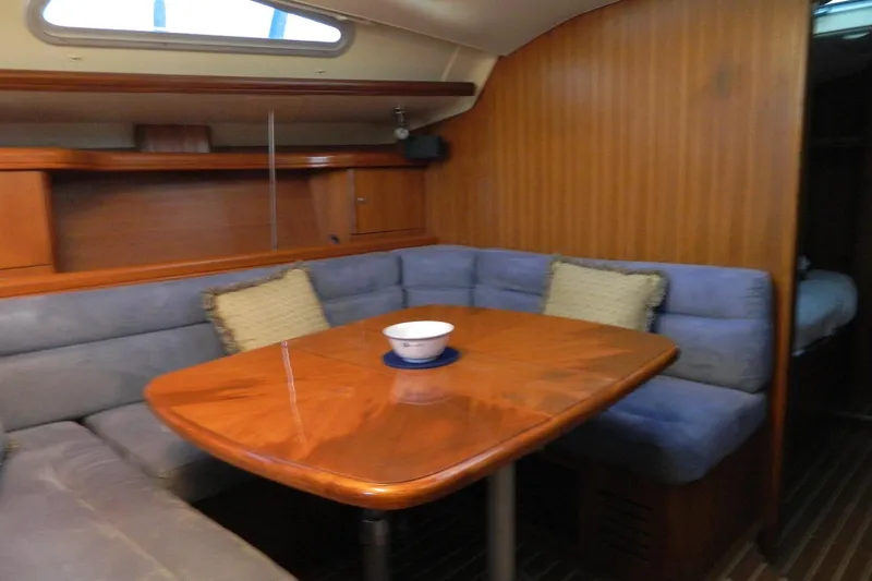 Slide: The Image of Interior of 2007 Hunter 41 AC sailboat with wooden table and blue cushioned seating. - 16