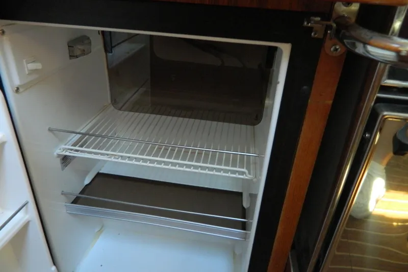 Slide: The Image of Empty refrigerator inside a 2007 Hunter 41 AC boat, featuring wire shelves. - 19