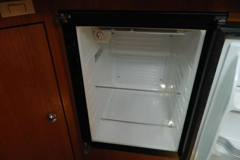 Slide: The Image of Empty refrigerator inside a 2007 Hunter 41 AC sailboat, featuring wooden cabinetry. - 21