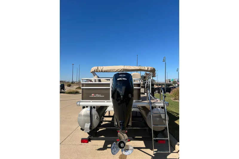 Slide: The Image of 2024 Sun Tracker SportFish 20 DLX pontoon boat with outboard motor, parked on pavement. - 2
