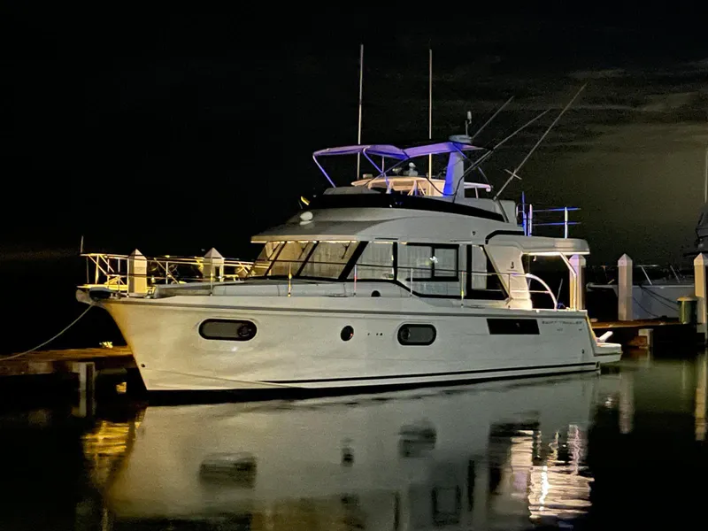 Slide: The Image of 2021 Beneteau Swift Trawler 41 Fly docked at night, reflecting on calm water. - 14