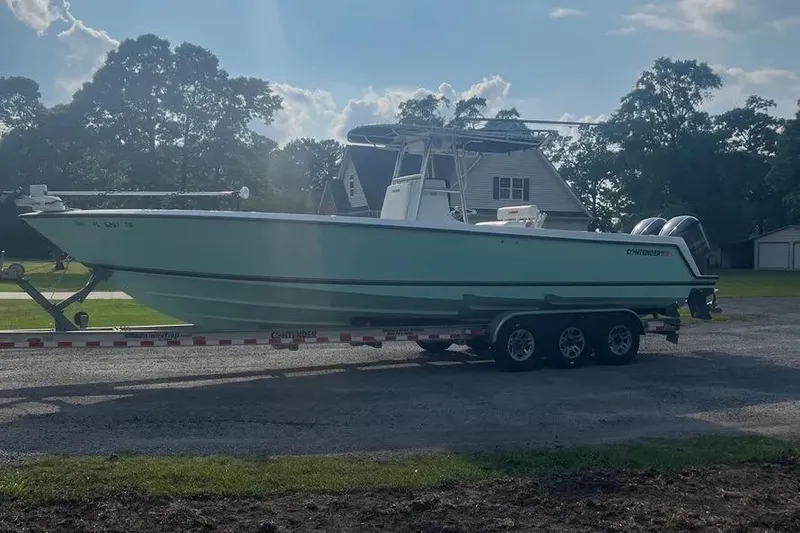 Slide: The Image of 2011 Contender 32 ST boat on trailer, parked outdoors near houses and trees. - 3