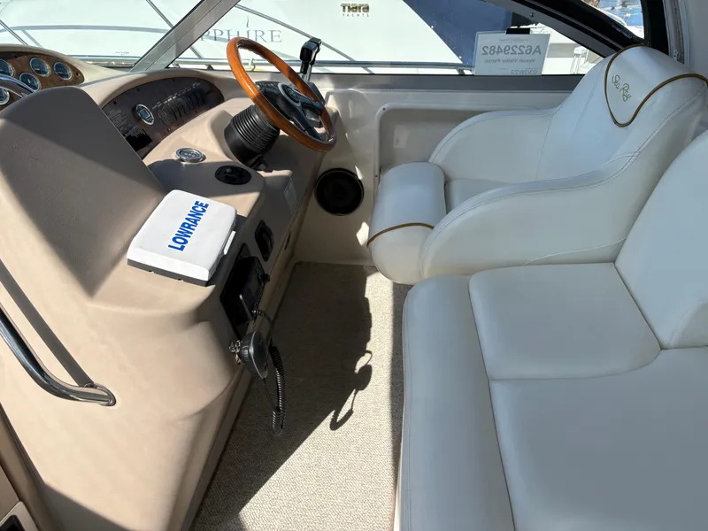 Slide: The Image of 1999 Sea Ray 340 Sundancer helm with white seating and wooden steering wheel. - 14