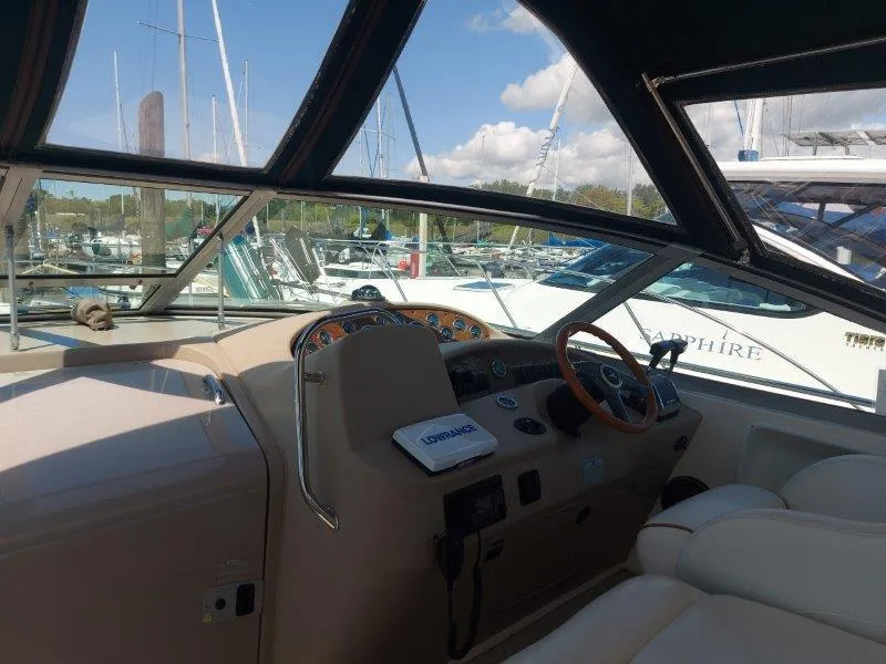 Slide: The Image of 1999 Sea Ray 340 Sundancer cockpit with steering wheel, dashboard, and marina view. - 42