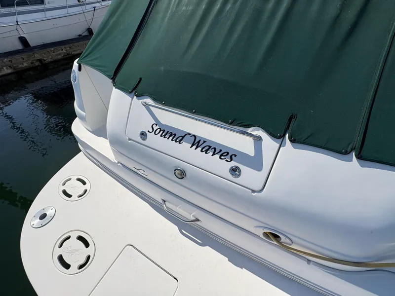 Slide: The Image of 1999 Sea Ray 340 Sundancer boat named "Sound Waves" with green cover at dock. - 6