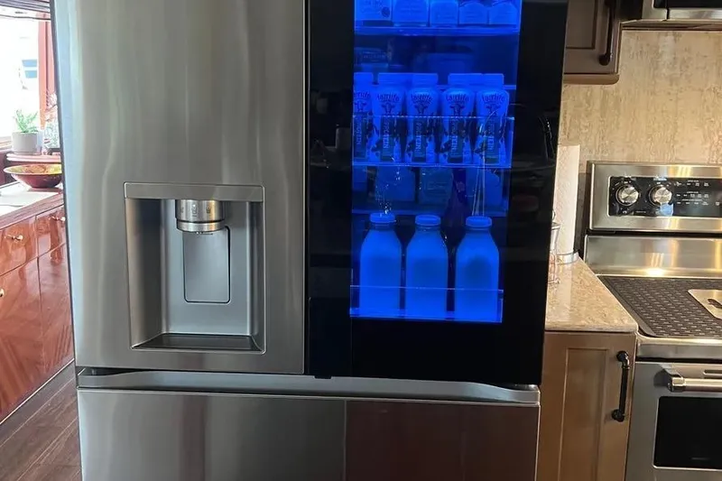 Slide: The Image of Modern kitchen with stainless steel refrigerator featuring a blue-lit display, aboard a 2004 Lazzara SC Motor Yacht. - 22