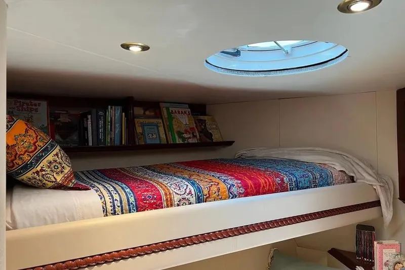 Slide: The Image of Cozy 2004 Lazzara SC Motor Yacht cabin with colorful bedding and books under a skylight. - 66